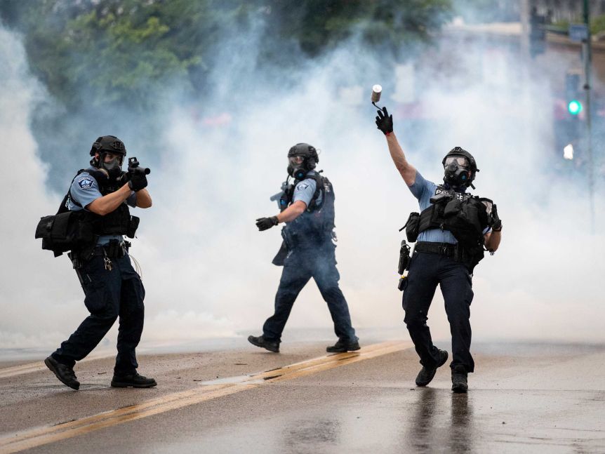 A police officer throws a tear gas canister
