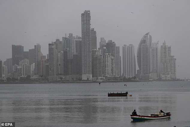 Fishermen carry on working on their boats as a cloud of dust from the Sahara desert covers the buildings of Punta Paitilla, in Panama City, Panama