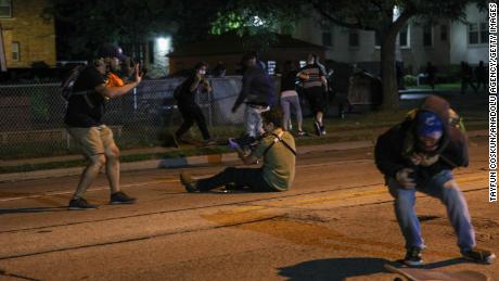A man with a gun takes aim at another person during a third night of protests in Kenosha.