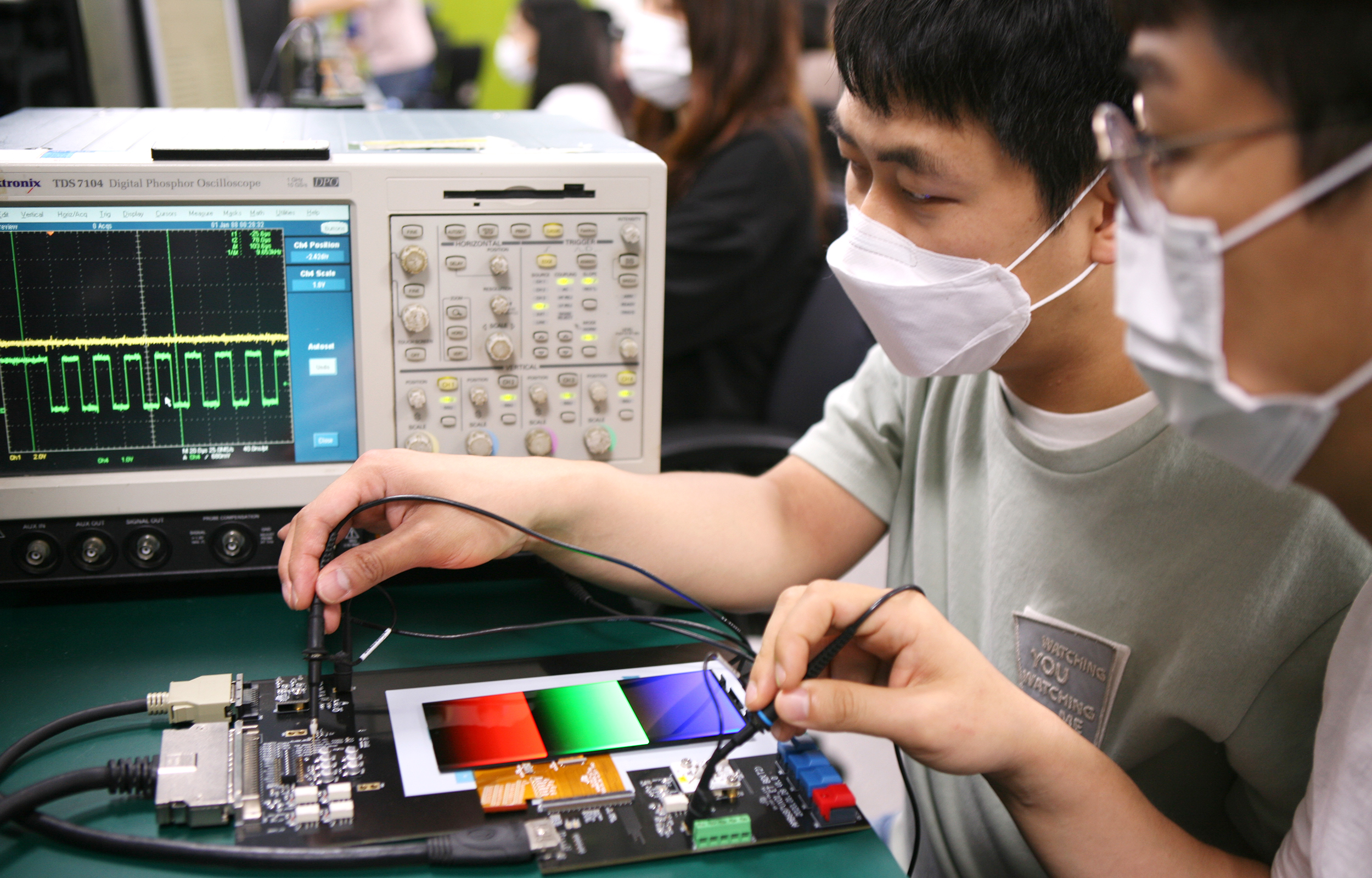 Engineers from Samsung Display are using testing devices to inspect frequency changes in display panels that feature adaptive frequency technology.