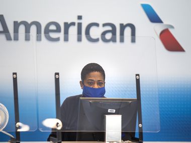 An American Airlines employee waits to help the next passenger check luggage in Terminal A at DFW International Airport.