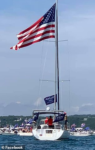 A boat sails by waving multiple Trump 2020 flags during the parade