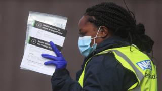 An NHS Test and Trace worker, holds self test kits at a testing centre in Bolton