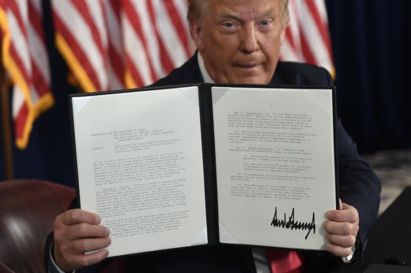 President Donald Trump holding up one of the four executive orders that he signed that addresses the economic fallout from the COVID-19 pandemic at his Trump National Golf Club in Bedminster, N.J., Saturday, Aug. 8, 2020. Trump signed the executive orders and bypassed the nation's lawmakers as he claimed the authority to defer payroll taxes and replace an expired unemployment benefit with a lower amount after negotiations with Congress on a new coronavirus rescue package collapsed. (AP Photo/Susan Walsh)