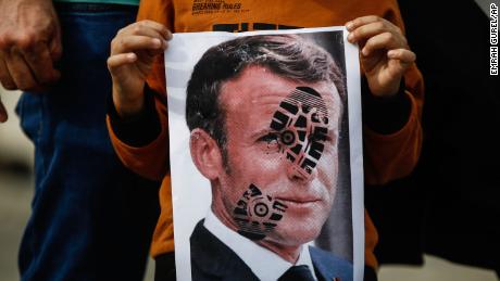 A child holds a photograph of Emmanuel Macron, stamped with a shoe mark, during a protest against France in Istanbul on October 25