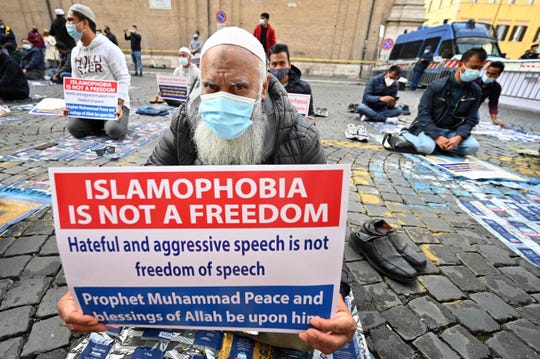 Muslim faithfuls hold placards as they pray during a gathering on Oct. 30, 2020, in central Rome called against Islamophobia and for boycotting France amid anger in the Islamic world over France's defense of the right to publish cartoons seen as offensive to Islam. -
