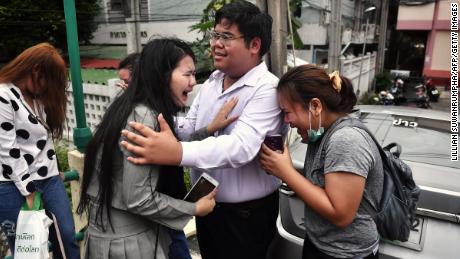 Pro-democracy activist Bunkueanun &quot;Francis&quot; Paothong comforts loved ones before he enters the Dusit police station to answer charges of harming Thailand&#39;s Queen Suthida on October 16, 2020. 
