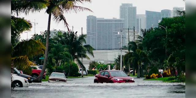 A car navigates a flooded street in the Melrose Manors neighborhood west of downtown Fort Lauderdale on Monday, Nov.9, 2020.