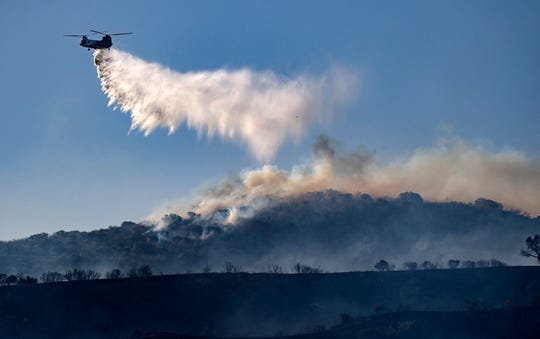 A helicopter drops retardant on the Silverado wildfire off Santiago Canyon Road where fierce winds have caused problems on Monday, Oct. 26, 2020, in Irvine, Calif.