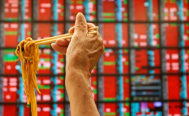 © Reuters. FILE PHOTO: A man eats his lunch of noodles while monitoring stock market prices inside a brokerage in Taipei