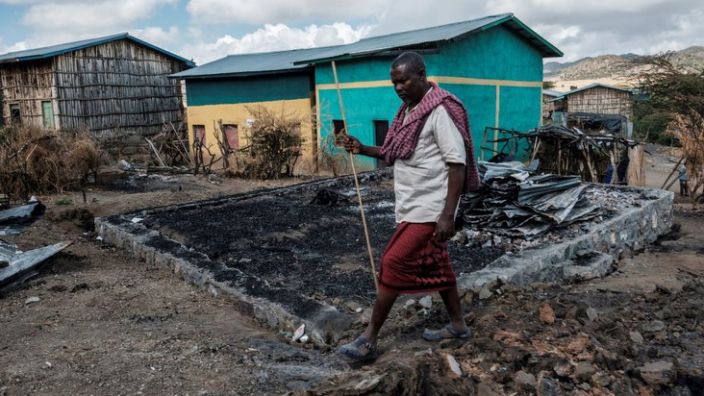 Addis Sissay, 49, walks in front of his destroyed house in the village of Bisober, in Ethiopia&#39;s Tigray region on December 9, 2020