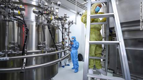 In this April 11, 2020, photo released by Xinhua News Agency, staff members check and clean equipments at a vaccine production plant of SinoPharm in Beijing.