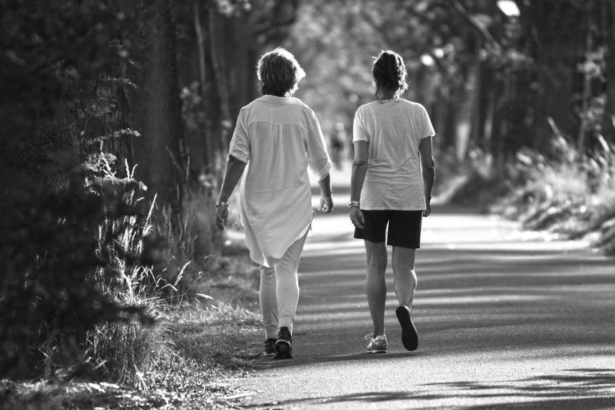 Black and white image of two women walking on a path outside