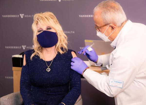 Singer Dolly Parton wore a sparkly navy blue knit top with cold-shoulder cutouts when she received her vaccination on March 2.
