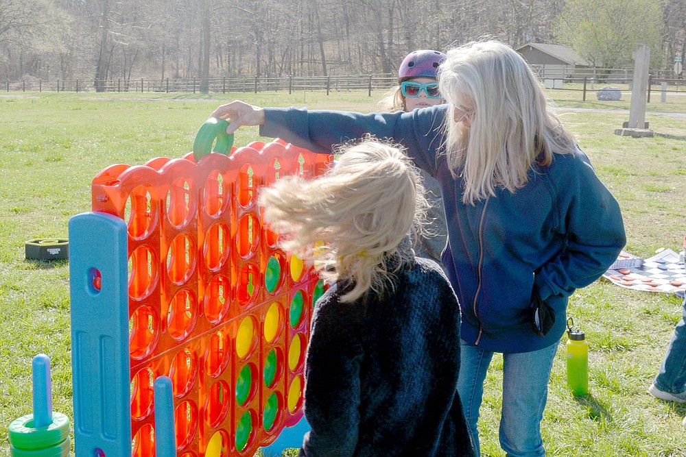 Marc Hayot/Herald-Leader Katy Thompson (center with Genevieve Thompson, front and Sarah Thompson, back), places a green piece into the giant Connect Four game as she plays with her daughters. The Thompsons were enjoying the day at Spring Break Bike Fest.