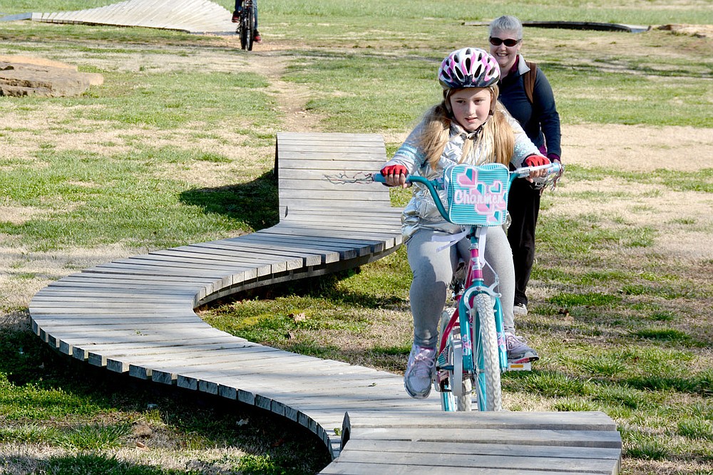 Marc Hayot/Herald-Leader Esther Baker rides her bike on the wooden bike course at City Lake Park as her mother looks on during Spring Break Bike Fest. The event held on Saturday gave people a chance to get out and enjoy some fresh air.