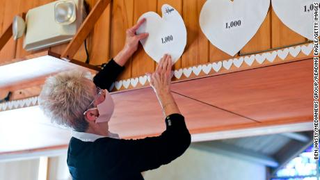 Christy Hylton, church council vice president prepares to put up a paper heart in One United Church of Christ in Kenhorst, Pennsylvania, to represent each 1,000 deaths from Covid-19 in the state on March 3, 2021.