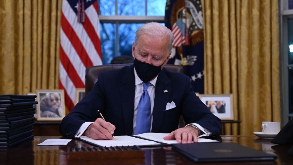 President Biden signing papers at his desk