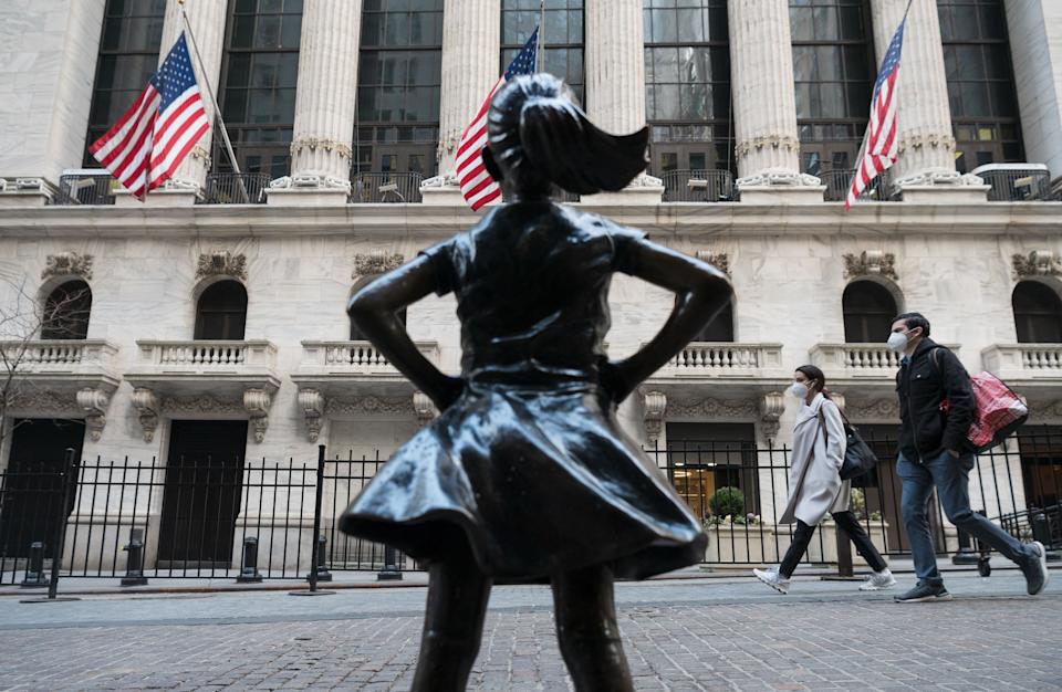 People walk past the New York Stock Exchange (NYSE) at Wall Street and the  &#39;Fearless Girl&#39; statue on March 23, 2021 in New York City. - Wall Street stocks were under pressure early ahead of congressional testimony from Federal Reserve Chief Jerome Powell as US Treasury bond yields continued to retreat. (Photo by Angela Weiss / AFP) (Photo by ANGELA WEISS/AFP via Getty Images)