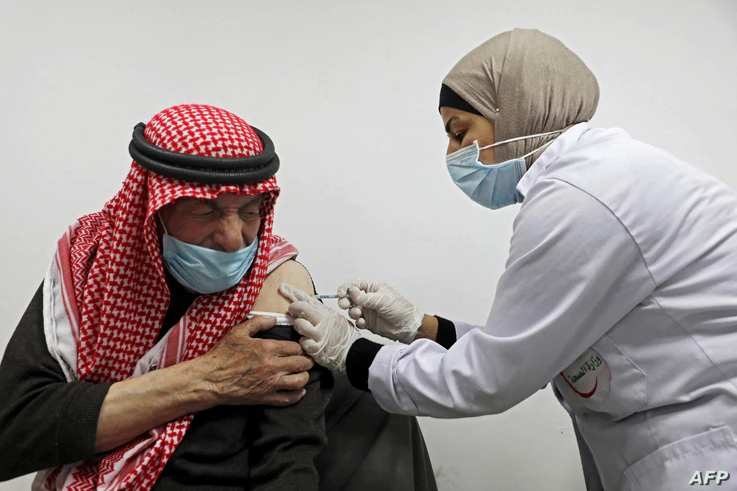 An elderly Palestinian man receives a shot of the Covid-19 coronavirus vaccine in the West Bank city of Nablus on March 22,…