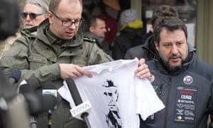 The Mayor of Przemysl, Wojciech Bakun, left, holds up a t-shirt with the likeness of Russian President Vladimir Putin as Italy’s League Party leader, Matteo Salvini, right, speaks with journalists outside the train station in Przemysl, Poland.