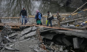 People cross the Irpin river near a destroyed bridge as they evacuate from Irpin town, amid Russia’s invasion of Ukraine, outside of Kyiv, Ukraine April 1, 2022.