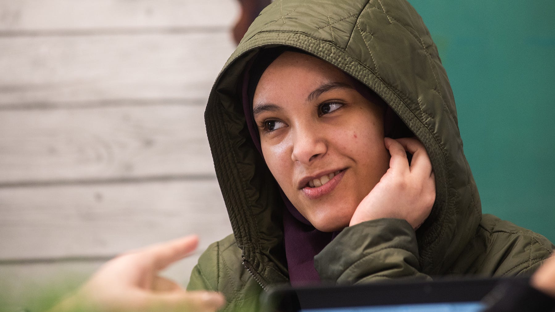 Hanan Ali, 16, listens through an earpiece that is translating what her teacher is saying from English to Arabic in real time during her class recently at South Middle School in Newburgh.