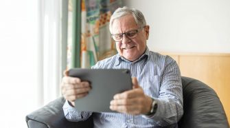 Senior man sitting at home using digital tablet for video calling. Mature man having online consultation with doctor.