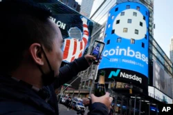 An employee of the Coinbase celebrates the cryptocurrency exchange company's stock offering in 2021. Just more than one year later, the company is reducing its staff because it expects an economic slowdown. (AP Photo/Richard Drew)
