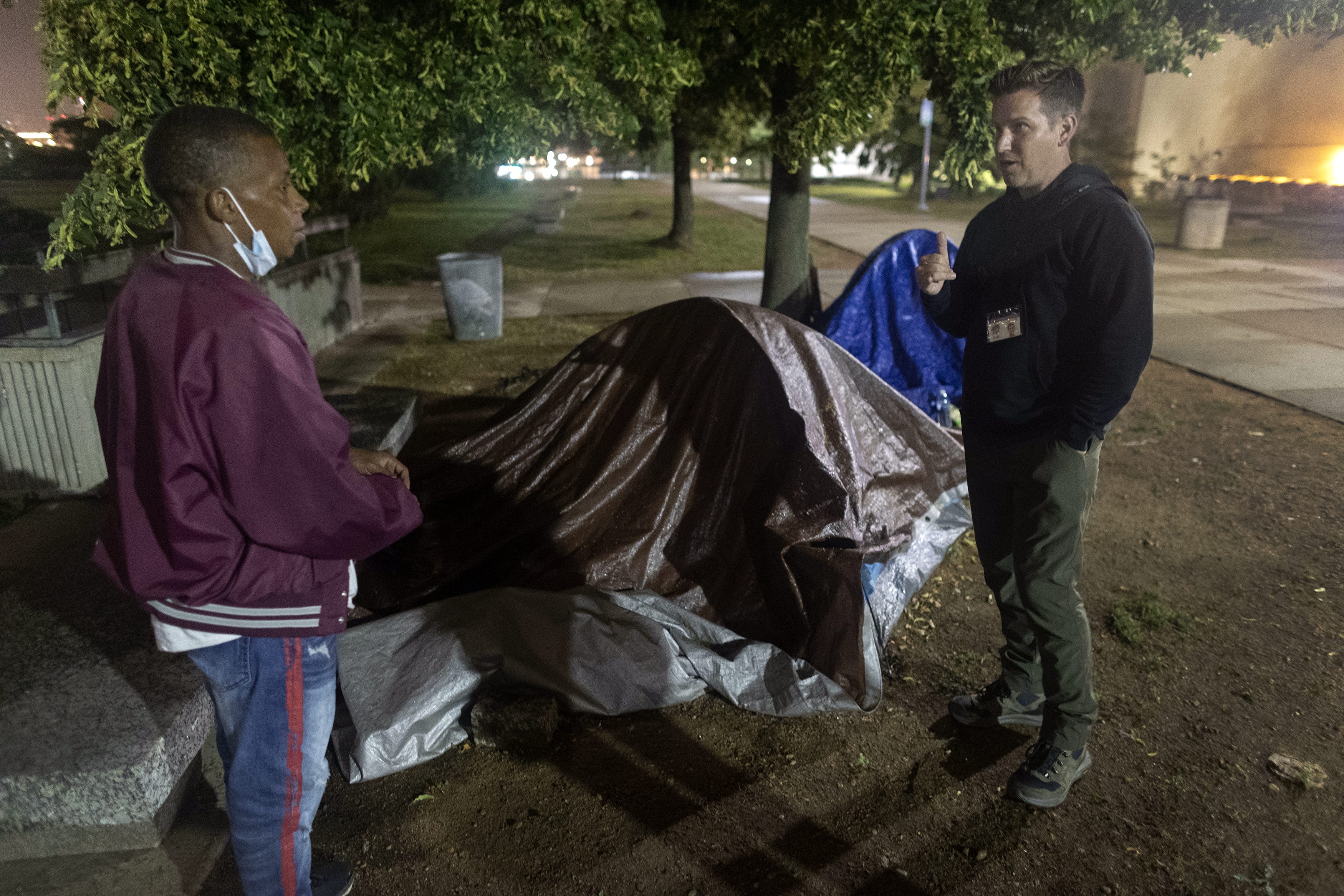 Eric Collins-Dyke, right, talks to Akeem Lawrence about getting a place to live while outside Lawrence's tent in MacArthur Square Park in downtown Milwaukee. Collins-Dyke is assistant administrator of supportive housing and homeless services for the Milwaukee County Housing Division.
