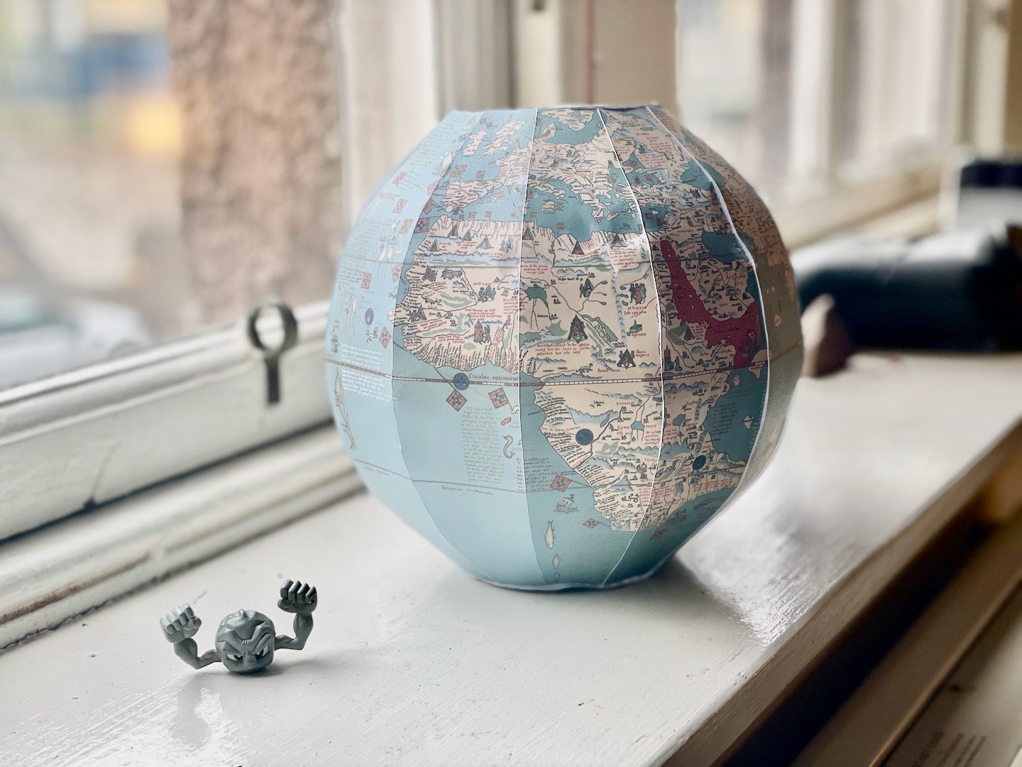A photograph of a paper globe with a diameter of 20 centimeters, showing Europe and Africa. A geodude is in the bottom-left corner.
