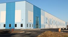 An Amazon warehouse with shades of lighter and darker blue against a blue sky.